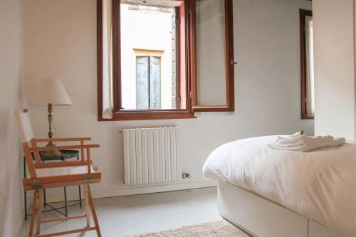 een slaapkamer met een bed, een stoel en een raam bij Erbe Canal View Private House in Venetië