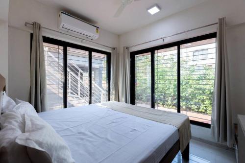 a bedroom with a bed and two large windows at Lotus 3BHK by SoulStays in Dapoli
