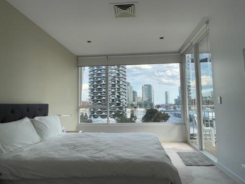 a bedroom with a bed and a large window at Docklands Luxury Penthouse Right Above The District Docklands in Melbourne
