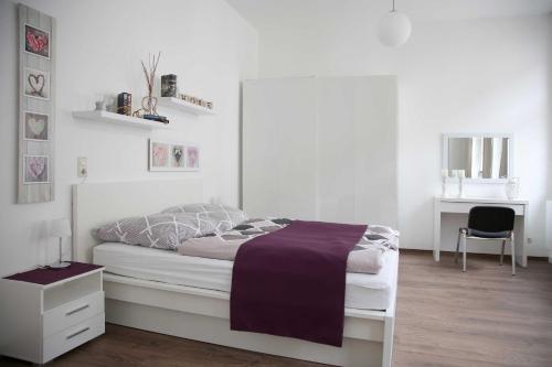 a white bedroom with a bed and a desk at Appartements am Markt in Greifswald