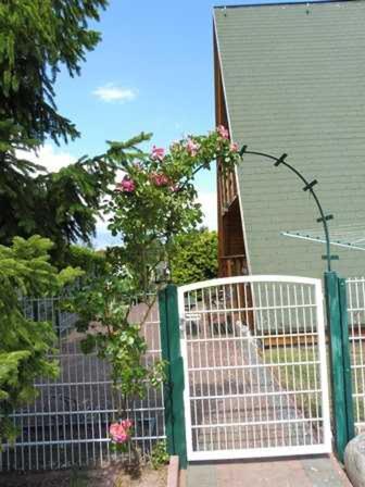 ユッケリッツにあるFerienhaus _Achterblick_ Gerlindeの家の隣に薔薇の門を持つ柵