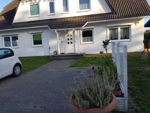 a white house with a car parked in front of it at Ferienwohnung am Teich in Lütow