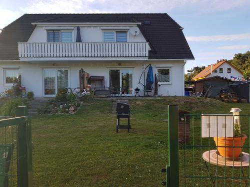 a white house with a fence in the yard at Ferienwohnung am Teich in Lütow