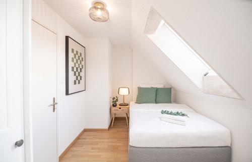 ein weißes Zimmer mit einem Bett und einem Fenster in der Unterkunft Modern 3BDR Duplex with Skyroof in Trendy Zurich West in Zürich