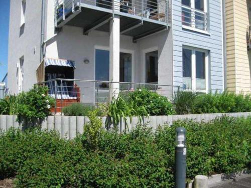 a house with a balcony and a fence and bushes at Ferienwohnungen Am Yachthafen in Greifswald