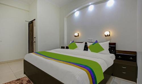 a bedroom with a large bed with green and colorful pillows at Treebo Trend Amexx Sector 55 in Gurgaon