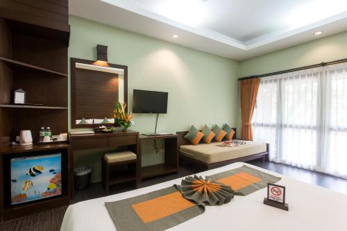 Baan Chaweng Beach Resort & Spa - SHA Extra Plus في شاطئ تشاوينغ: غرفة معيشة مع أريكة وتلفزيون