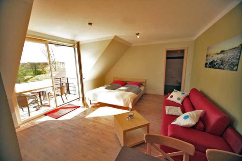 ein Wohnzimmer mit einem roten Sofa und einem Bett in der Unterkunft Ferienappartements Jack & Richies in Greifswald