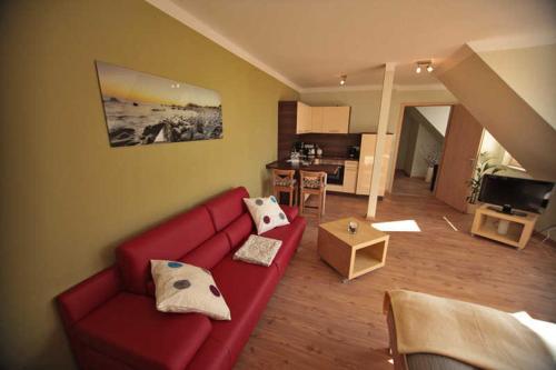 ein Wohnzimmer mit einem roten Sofa und einer Küche in der Unterkunft Ferienappartements Jack & Richies in Greifswald
