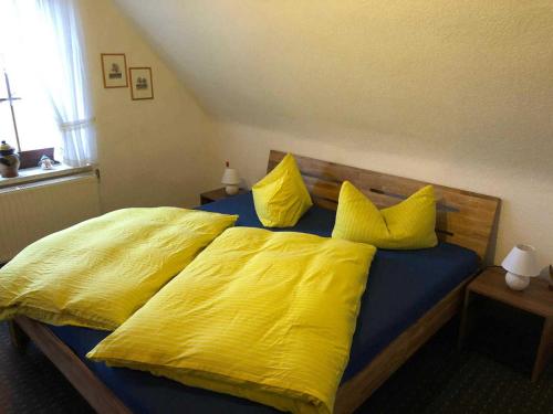 a yellow bed with yellow sheets and pillows at Ferienwohnungen Familie Mickley in Behrenhoff