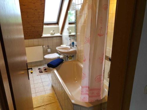 a bathroom with a bath tub and a sink at Ferienwohnungen Familie Mickley in Behrenhoff