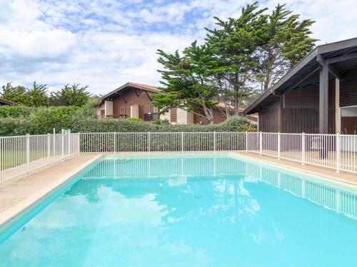 une grande piscine bleue en face d'une clôture dans l'établissement Villa Mitoyenne avec Jardin, Proche Plage à Seignosse, Piscine, Parking Privé et Wifi - FR-1-239-421, à Seignosse