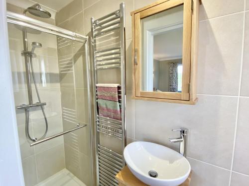 ein Bad mit einem Waschbecken, einer Dusche und einem Spiegel in der Unterkunft Morwennol in Saint Merryn