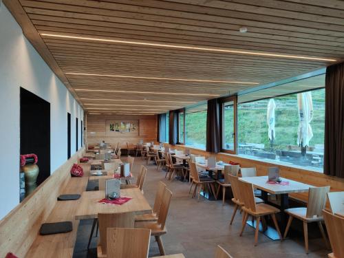 a dining room with tables and chairs and windows at Starkenfeldhütte in Rodengo