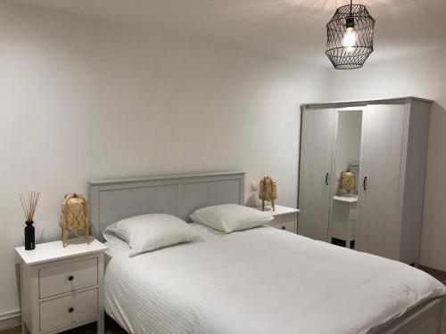 1 dormitorio con 1 cama blanca y 2 mesitas de noche en Joli appartement dans une maison remise à neuf en Mittelhausbergen