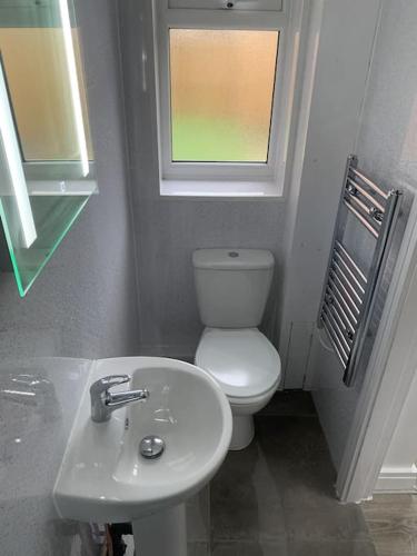 a bathroom with a toilet and a sink and a window at Town Centre Getaway in Southport