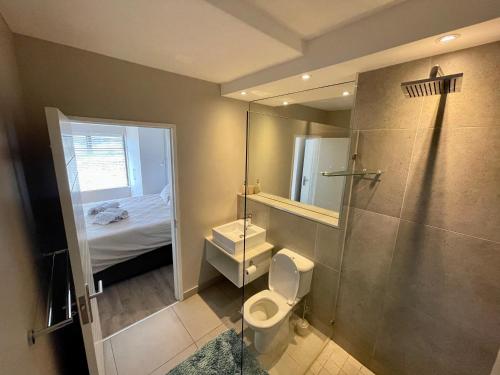 uma casa de banho com um WC, um chuveiro e uma cama. em Castleton Self-Catering Accommodation em Plettenberg Bay