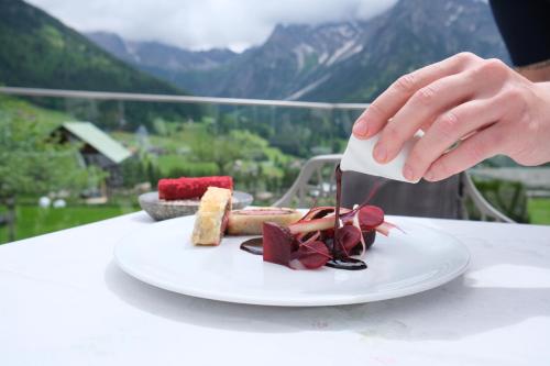 a person eating a plate of food on a table at Haller's Geniesserhotel in Mittelberg