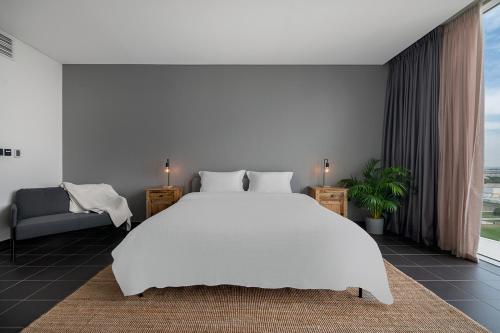 a white bedroom with a large white bed and a couch at Emirates Sports Hotel, Dubai Sports City in Dubai