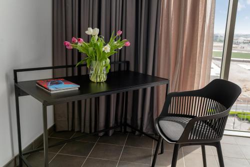 a desk with a vase of flowers and a chair at Emirates Sports Hotel, Dubai Sports City in Dubai