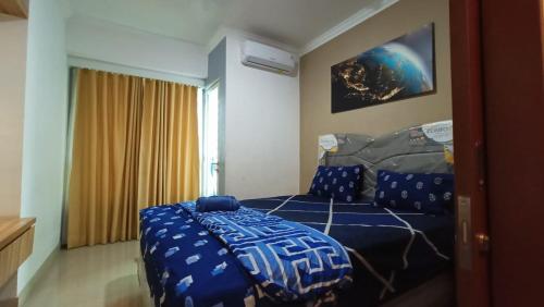 una camera con letto e piumone blu di Mushroom Apartment Grand Kamala Lagoon by Mrs Sewa a Pekayon Satu
