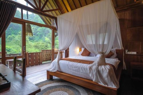 a bedroom with a canopy bed with a large window at Yeh Baat Jatiluwih by The Lavana in Jatiluwih