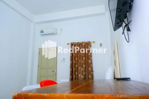 a room with a table and a red partner sign on the wall at Fortuner Homestay Syariah Makassar Mitra RedDoorz in Pampang