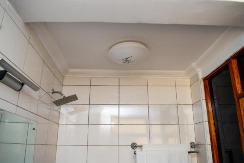 a bathroom with a shower with a white tiled wall at Astorian Grand Hotel Naivasha in Naivasha