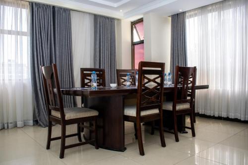 a dining room table with chairs and curtains at Astorian Grand Hotel Naivasha in Naivasha