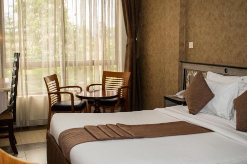 a hotel room with a bed and a table and chairs at Astorian Grand Hotel Naivasha in Naivasha