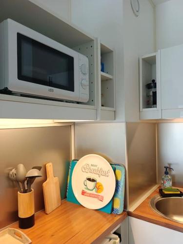 a small kitchen with a microwave above a counter at Charmant Studio avec vue sur le port et falaises in Fécamp