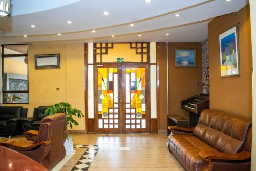 a lobby with a leather couch and a glass door at Astorian Grand Hotel Naivasha in Naivasha