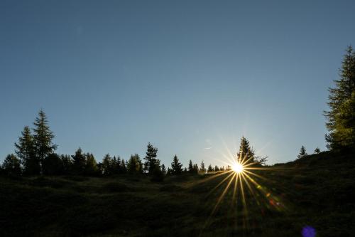 a sun setting on a hill with trees in the background at Starkenfeldhütte in Rodengo