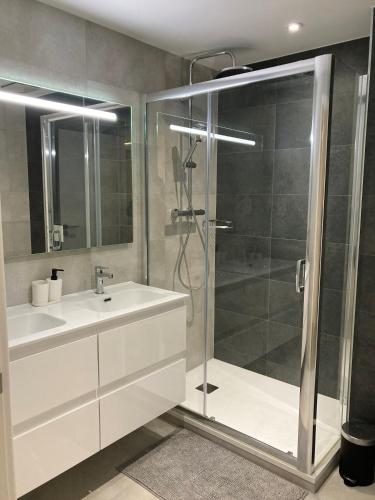 a bathroom with a white sink and a shower at E1 Suites & Spa aparthotel style - Gym & Spa in Gibraltar