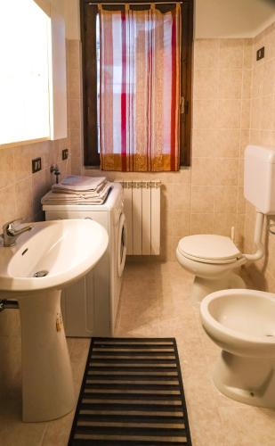 a bathroom with a sink and a washing machine at La Quiete - Casa Vacanza in Ranzanico