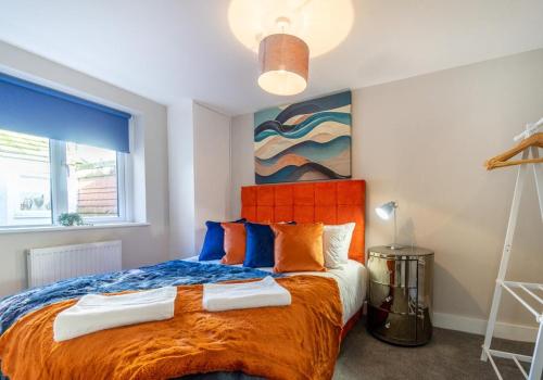 a bedroom with a large bed with an orange headboard at Station Lodge By My Getaways in Brighton & Hove