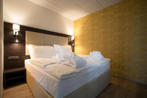 a bedroom with a large white bed with towels on it at Hotel Slunný Dvůr in Jeseník