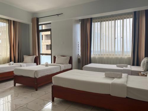 a hotel room with two beds and a window at Panama Inn Moshi in Moshi