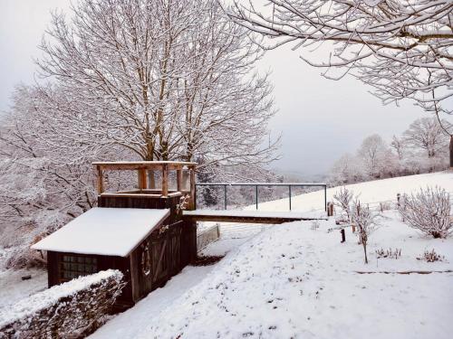 a snow covered park with a bench and a bridge at La Vieille Forge B&B in Houffalize