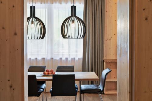 a dining room with a table and chairs and two lights at Natürlich Hell. Aparthotel & Camping in Fügen