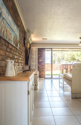 a kitchen with white cabinets and a brick wall at The Gums Anchorage in Bellara
