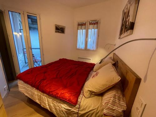 une chambre avec un lit avec une couverture rouge dans l'établissement T2 30m2 plein centre, lit fait, linge fourni, WIFI, à Cauterets