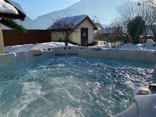 a swimming pool in the snow with a house at L'Augustine - Spa privé & Vue Montagne in Saint Avre la Chambre