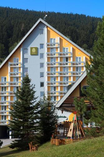 a large building with a clock on the side of it at Pinia Hotel & Resort in Špindlerův Mlýn