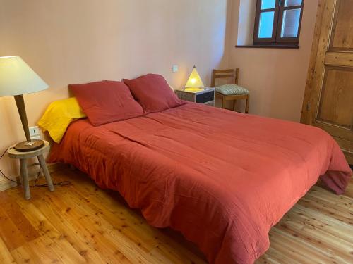 une chambre avec un grand lit avec une couverture rouge dans l'établissement Le Pied de Ville Pouzenc, à Embrun