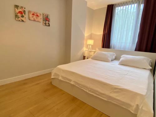 Schlafzimmer mit einem Bett mit weißer Bettwäsche und einem Fenster in der Unterkunft New Apartment by MSuites in Kadikoy 01 in Istanbul