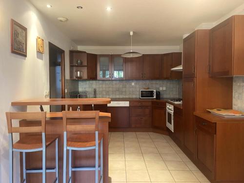 une cuisine avec des armoires en bois et une table et des chaises dans l'établissement Le Pied de Ville Pouzenc, à Embrun