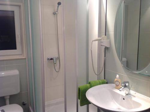 a bathroom with a sink and a shower with a mirror at Apartmani ROBERTA in Bol