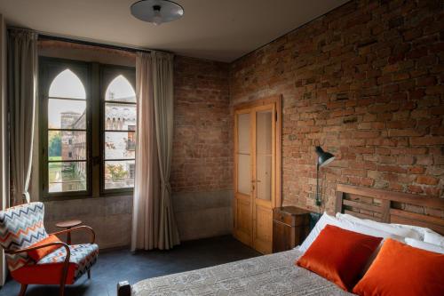 - une chambre avec un mur en briques, un lit et une chaise dans l'établissement Agriturismo Padernello, à Borgo San Giacomo