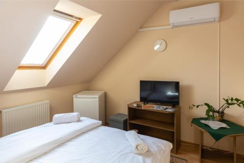 a attic bedroom with a bed and a tv at Betli Panzió in Zalaegerszeg